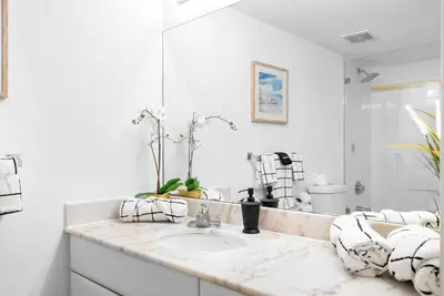 a white bathroom with a sink and a mirror at Stylish Condo with Panoramic Ocean Views in Miami