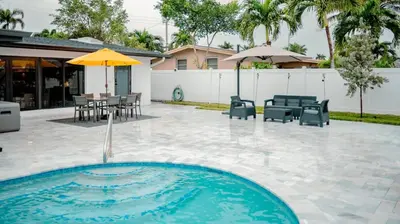 a pool with chairs and a table and an umbrella at Bimini Bliss Waterfront Pool Retreat in Fort Lauderdale