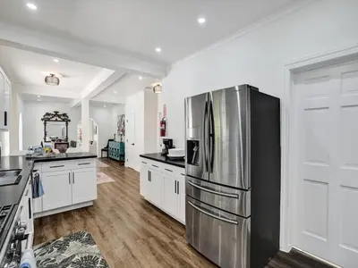 a kitchen with a stainless steel refrigerator and white cabinets at Classic 5 Bedroom 4 Bathroom Pool Home in Hollywood