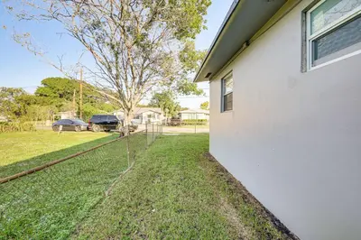 a white house with a fence next to a yard at 3 Mi to Port Everglades Modern Getaway with Yard in Dania Beach