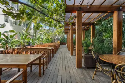 an outdoor patio with wooden tables and chairs at Bluebird Suites at The Apex Miami in Miami Beach