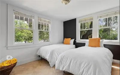 two beds in a white room with windows at Historic Sailboat Bend Home 5 Min to Las Olas 4 miles to the Beach in Fort Lauderdale