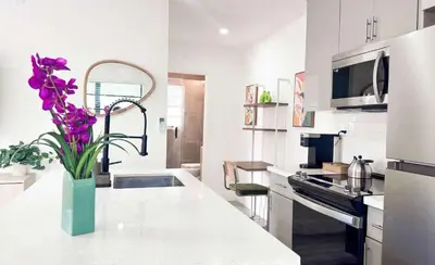 a kitchen with a vase of purple flowers on a counter at Cloud Nine - Wilton Drive Jacuzzi Backyard in Fort Lauderdale