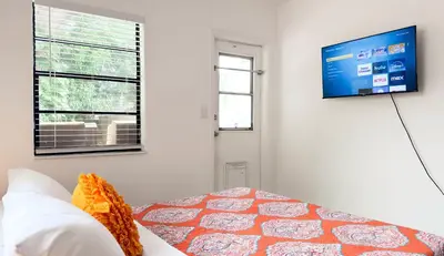 a bedroom with a tv on the wall and a bed at Cloud Nine - Wilton Drive Jacuzzi Backyard in Fort Lauderdale