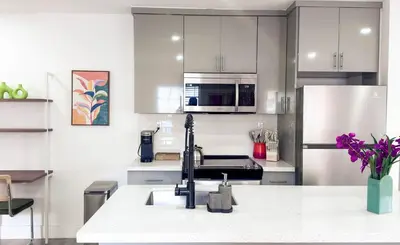 a kitchen with white cabinets and stainless steel appliances at Cloud Nine - Wilton Drive Jacuzzi Backyard in Fort Lauderdale