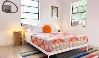 a bedroom with a bed with an orange pillow on it at Cloud Nine - Wilton Drive Jacuzzi Backyard in Fort Lauderdale