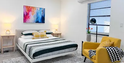 a bedroom with a bed and a yellow chair at The Hideaway - Wilton Manors in Fort Lauderdale