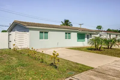 a white house with a fence and a driveway at 4 BR home with private pool in Fort Lauderdale