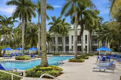 a resort pool with blue chairs and palm trees at Spacious 1BR Loft Villa - Pool Golf - Doral Downtown in Miami