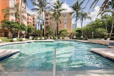 a large swimming pool with palm trees and buildings at The Yacht Club at Aventura Miami 8304 in Aventura