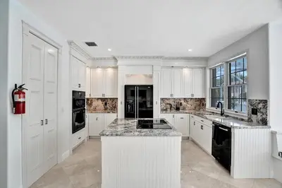 a kitchen with white cabinets and black appliances at 6BR Elegant Hollywood Lakes Mansion with Private Pool & Spa in Hollywood