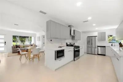 a kitchen with white cabinets and a table and chairs at 4BR Lakefront Heated Pool -Jacuzzi -Basket -Sauna in Fort Lauderdale