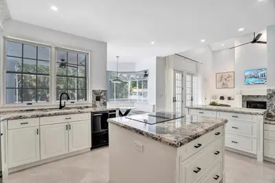 a kitchen with white cabinets and granite counter tops at 6BR Elegant Hollywood Lakes Mansion with Pool & Spa home in Hollywood