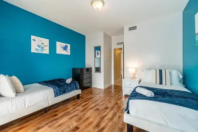 two beds in a room with blue walls and wooden floors at Salty Fox 5BD Oasis w Spa, Beach & Downtown in Fort Lauderdale