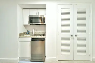 a kitchen with white cabinets and a stainless steel refrigerator at Luxury Studio at The Ritz-Carlton Key Biscayne in Miami