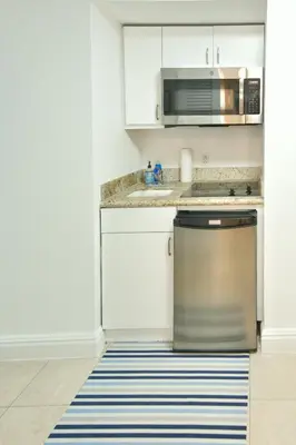 a kitchen with white cabinets and a stainless steel dishwasher at Luxury Studio at The Ritz-Carlton Key Biscayne in Miami