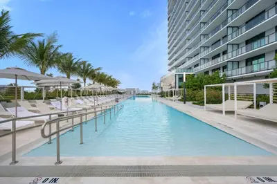 a swimming pool with chairs and umbrellas next to a building at NOK Amazing 1 BR in Miami Beach in Miami Beach