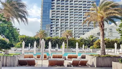 a pool with chairs and palm trees and a building at South Beach Amazing Ocean View in Miami Beach