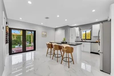 a kitchen with white cabinets and a counter with stools at Azure Coastal Breeze in North Miami Beach