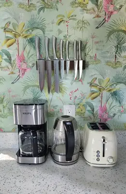 a group of knives hanging on a wall next to appliances at LUSH TROPICAL STUDIO in FT LAUDEDALE'S HISTORICAL SAILBOAT BEND NEIGHBORHOOD in Fort Lauderdale