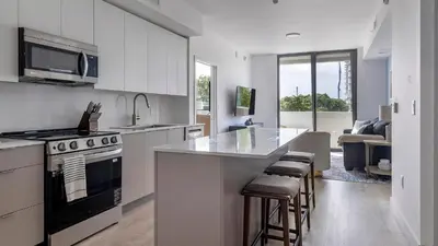 a kitchen with white cabinets and a kitchen island with bar stools at Landing Chic 2BD Clubhouse Yoga Studio in North Miami