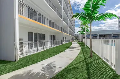 a sidewalk next to a building with a palm tree at Landing Incredible 3BD Pool Gym in Naranja