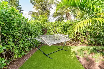 a hammock sitting on the grass in a garden at Stylish 2BR Oasis with Pool Mini Golf & BBQ in Fort Lauderdale