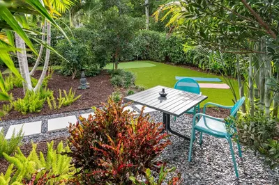 a picnic table and two chairs in a garden at Stylish 2BR Oasis with Pool Mini Golf & BBQ in Fort Lauderdale