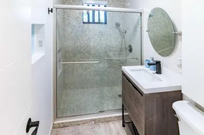 a bathroom with a shower with a sink and a mirror at Stylish 2BR Oasis with Pool Mini Golf & BBQ in Fort Lauderdale