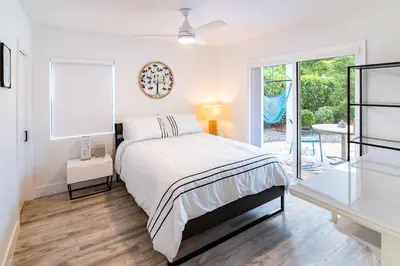 a white bedroom with a bed and a sliding glass door at Stylish 2BR Oasis with Pool Mini Golf & BBQ in Fort Lauderdale