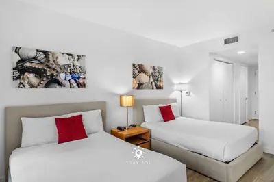 two beds with red pillows in a white room at Amazing Apartment with Bay View Balcony Near Beach in Hallandale Beach