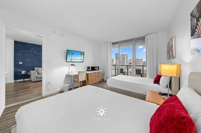 a bedroom with two beds and a desk with a tv at Amazing Apartment with Bay View Balcony Near Beach in Hallandale Beach