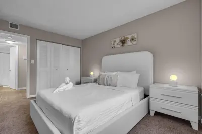 a white bedroom with a large bed and two night stands at Stylish 2BR in North Miami with Free Parking in North Miami