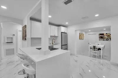 a white kitchen with a table and a dining room at Oasis With Pool and Putting Green in Hollywood