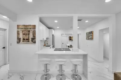 a white kitchen with a counter and stools at Oasis With Pool and Putting Green in Hollywood