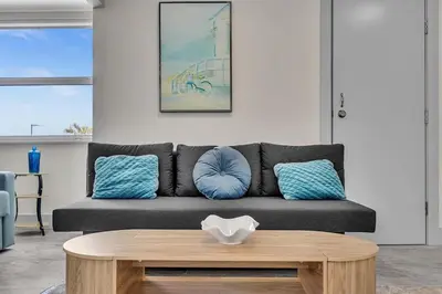 a living room with a black couch with blue pillows at Santorini Blu Spacious 2BR Beachfront Suite in Hollywood