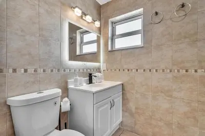 a bathroom with a toilet and a sink and a mirror at Santorini Blu Spacious 2BR Beachfront Suite in Hollywood