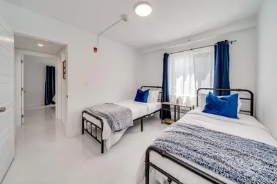 a bedroom with two beds and a window with blue pillows at Wynwood Charm, at the Heart of the Art! in Miami