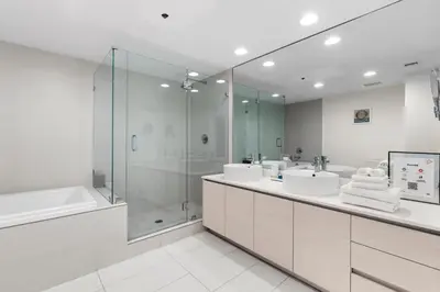 a white bathroom with two sinks and a shower at Luxury Oceanview Condo with Private Foyer at Beachwalk Resort in Hallandale Beach