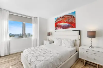 a white bedroom with a bed and a window at Luxury Oceanview Condo with Private Foyer at Beachwalk Resort in Hallandale Beach