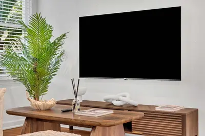 a living room with a table with a tv on a wall at Victoria Park Oasis Walk to las Olas Beach in Fort Lauderdale