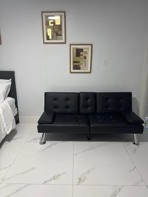 a black couch sitting in a white room at Beautiful 1 bedroom Studio located in Miramar in Miramar