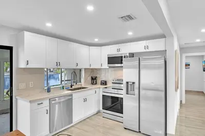 a kitchen with white cabinets and a stainless steel refrigerator at Waterfront Modern Hollywood Hard Rock airport in Fort Lauderdale
