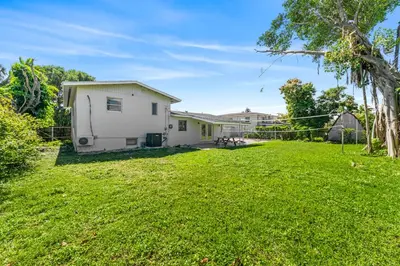 a yard with a white house and a grassy field at Casa Sol - 4 Bedroom 2 Bath - 7 beds - Affordable Stays For Large Groups in Ives Estates
