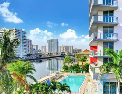 a building with a swimming pool next to a body of water at Cozy studio near beach Nice views in Hallandale Beach