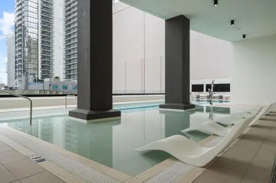 a swimming pool with white chairs in a building at Luxury Condo at District 225 - Downtown Miami Prime Location in Miami