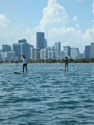 two people on paddle boards in the water with a city at Brickell Condos by Vibras Concierge in Miami