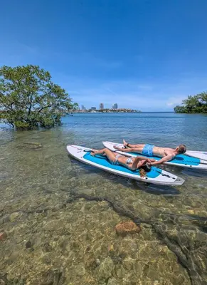 two people laying on paddle boards in the water at Brickell Condos by Vibras Concierge in Miami