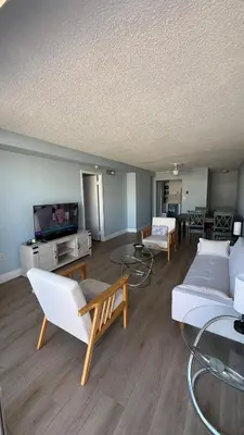 a living room with white furniture and a flat screen tv at Canal-front two-bedroom condo near Sunny Isles in North Miami Beach