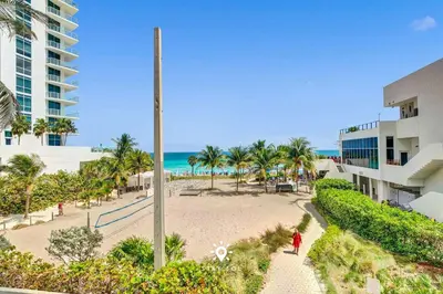 a person walking down a sidewalk next to a beach at Beautiful Balcony 2BR Resort in Hollywood